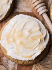 A closeup of a single sourdough brown butter cornbread cookies with honey butter cream frosting is shown.