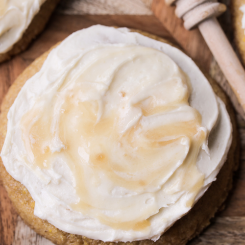 A closeup of a single sourdough brown butter cornbread cookies with honey butter cream frosting is shown.