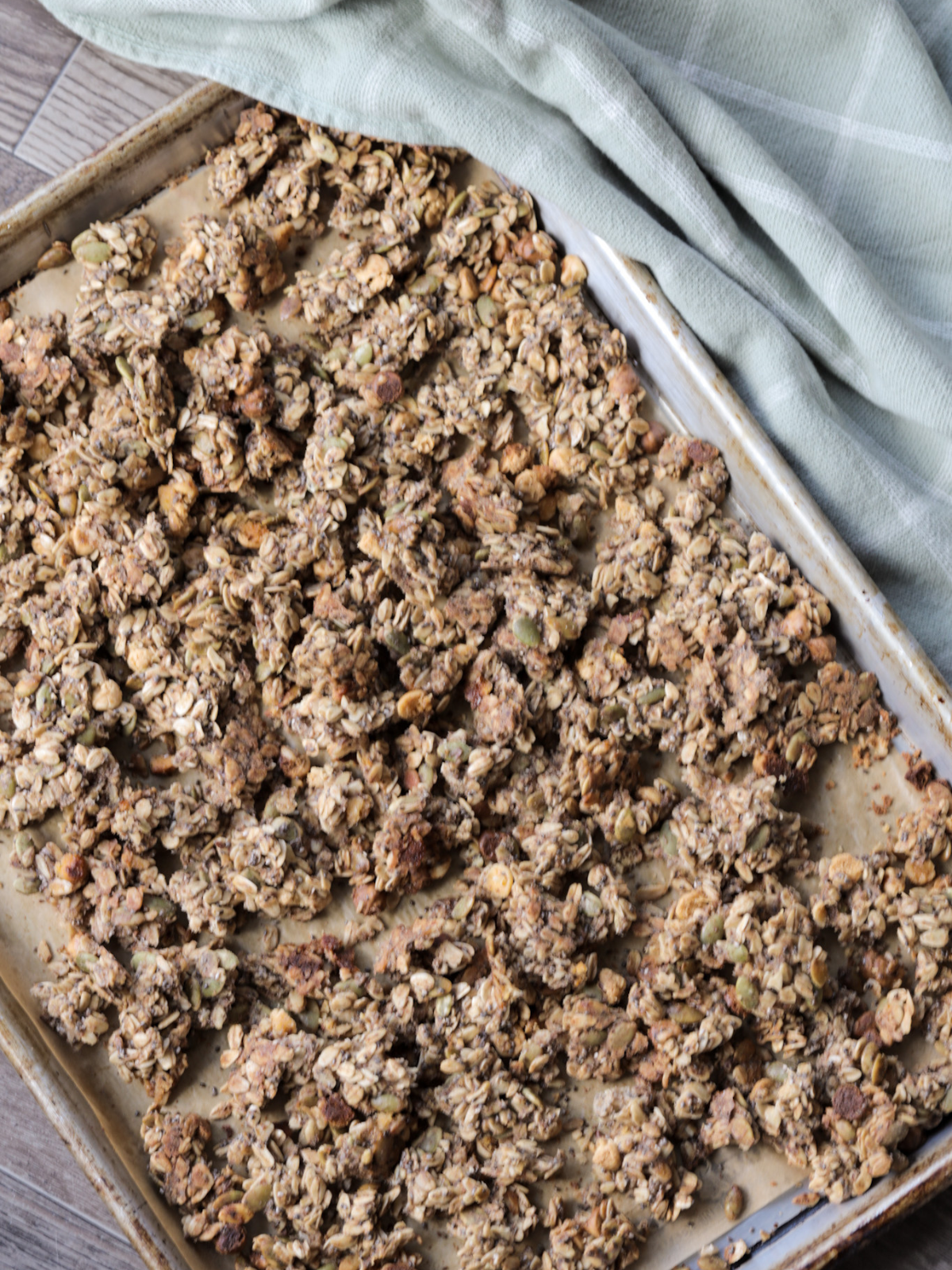 Freshly baked, crunchy sourdough granola rests on a baking sheet.