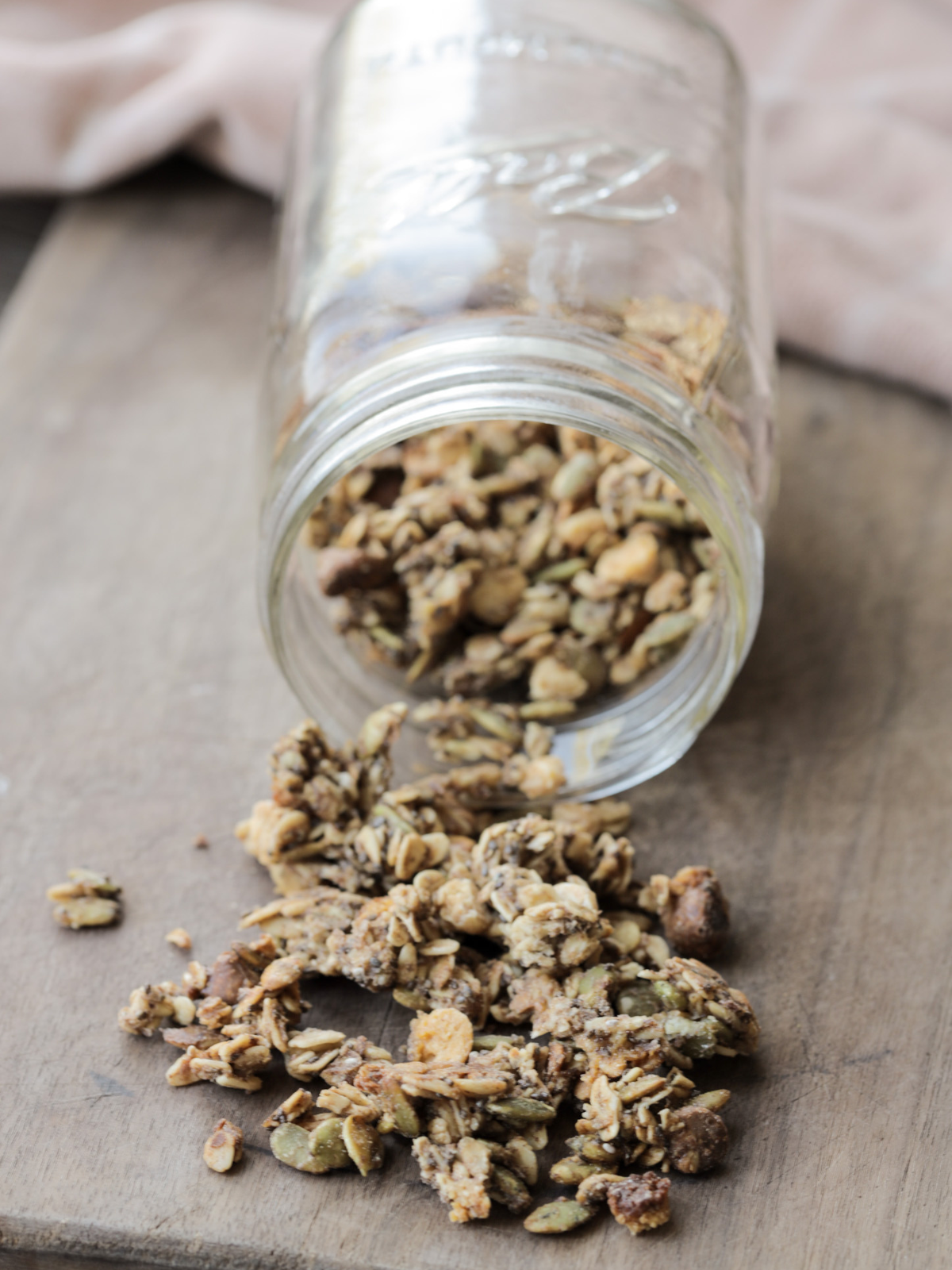 Sourdough discard granola is shown spilled out of a glass jar. 