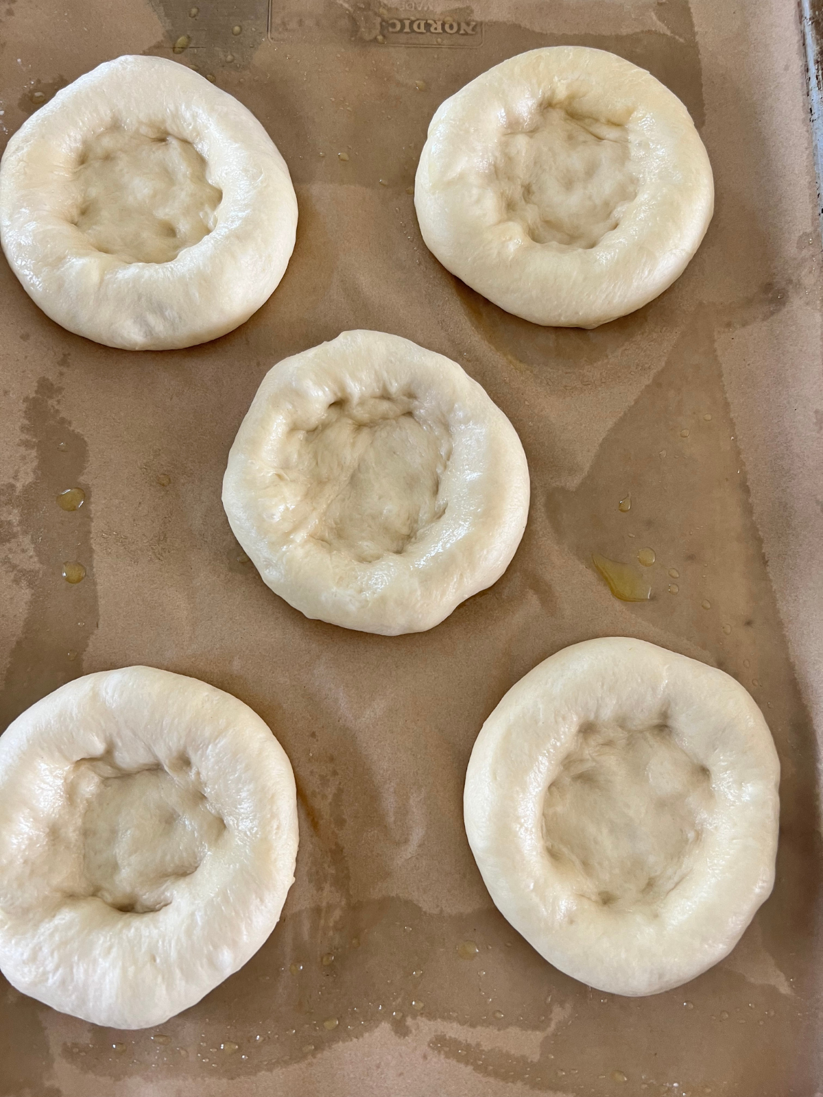 The sourdough lemon curd cream cheese buns have been shaped and are resting on the parchment lined baking sheet preparing for the filling.