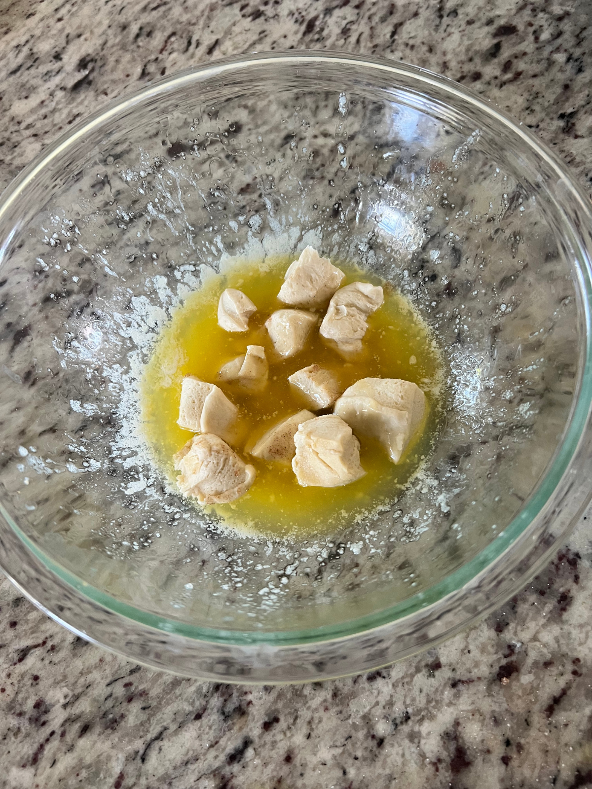 The dough pieces sit in the bowl of melted butter.