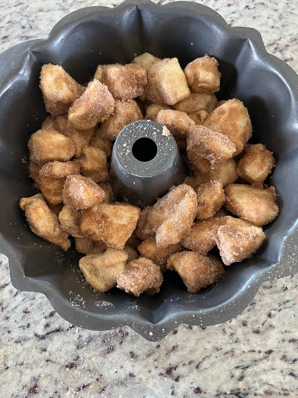 The sourdough monkey bread dough pieces sit in a greased Bundt pan.