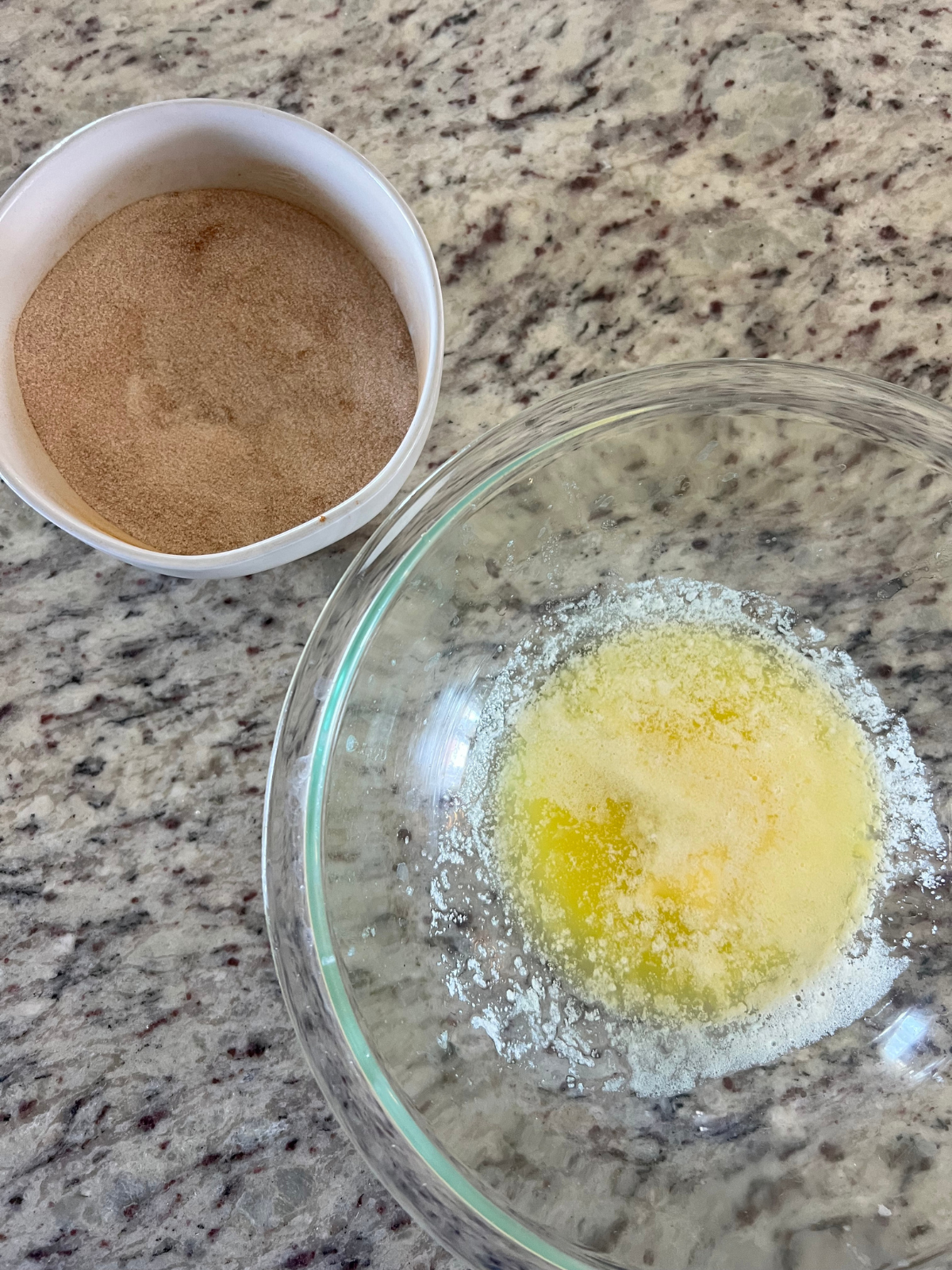 The cinnamon sugar mixture sits in one bowl and the melted butter sits in another.