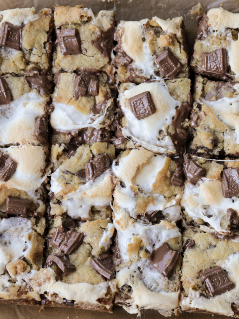 Gooey marshmallow and melty milk chocolate on top of a sourdough discard s'mores cookie bar cut into squares.