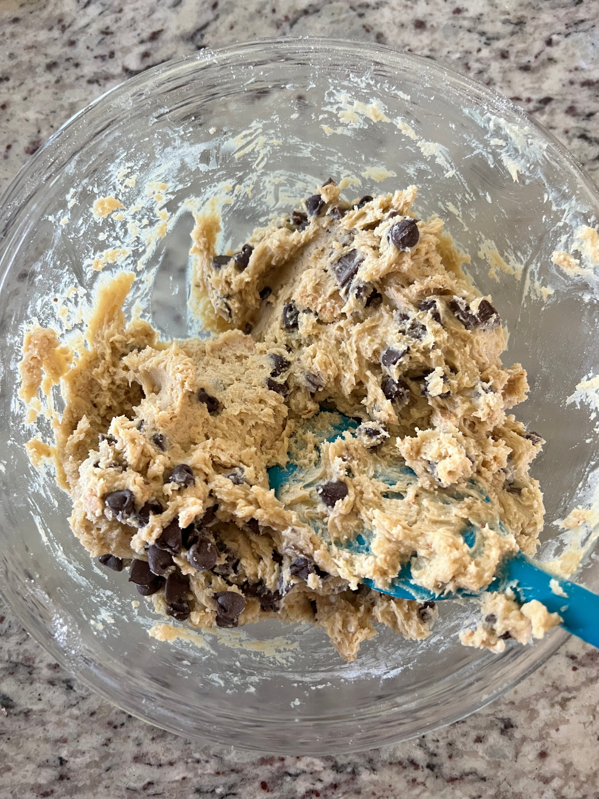 The sourdough s'mores cookie dough sits in a glass mixing bowl with the chopped Hershey's bars and chocolate chips mixed in.