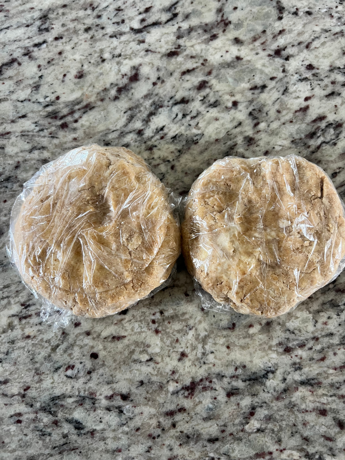 The sourdough s'mores pop tart dough is split into two discs, each wrapped in plastic wrap.