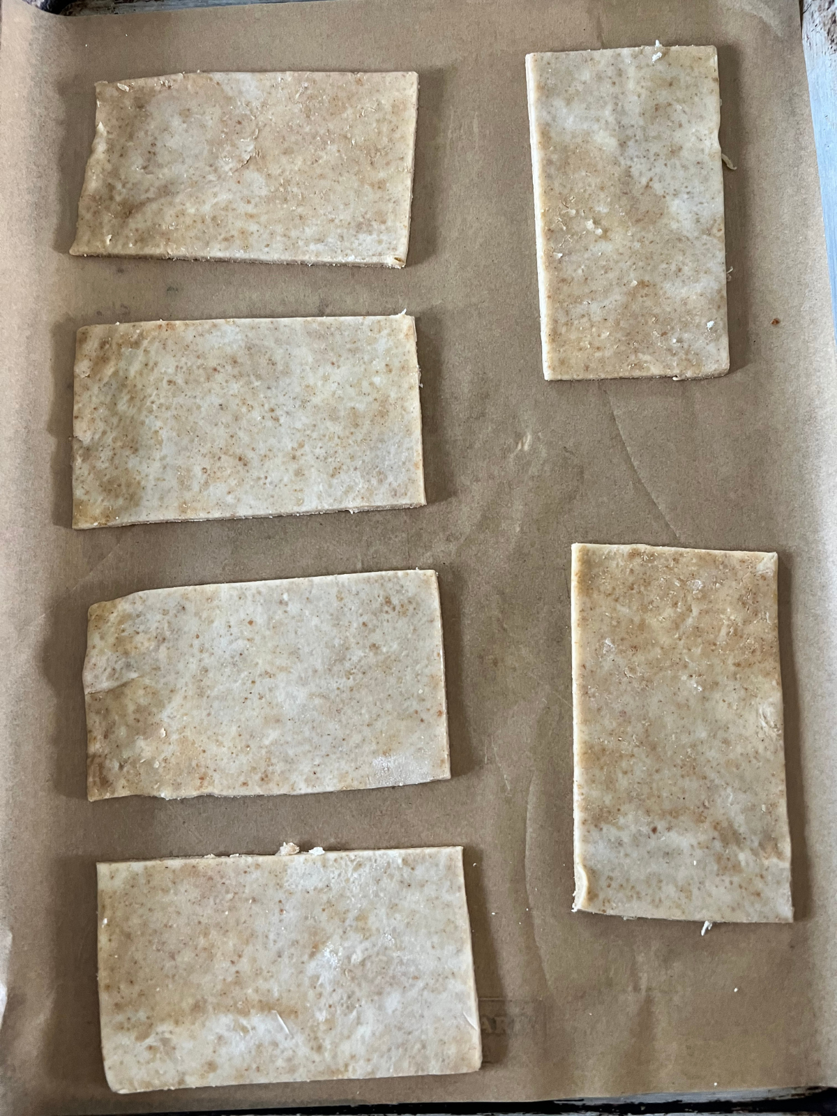 The sourdough s'mores pop tart dough is cut into rectangles and rest on a parchment paper-lined baking sheet to prepare for filling and topping with another dough rectangle.