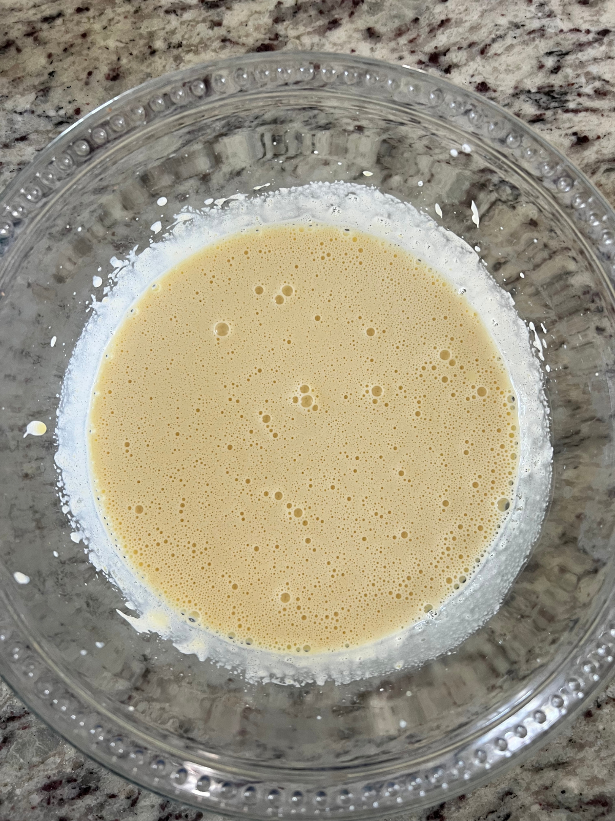 The wet ingredients for the sourdough tres leches cake sit in a glass mixing bowl.
