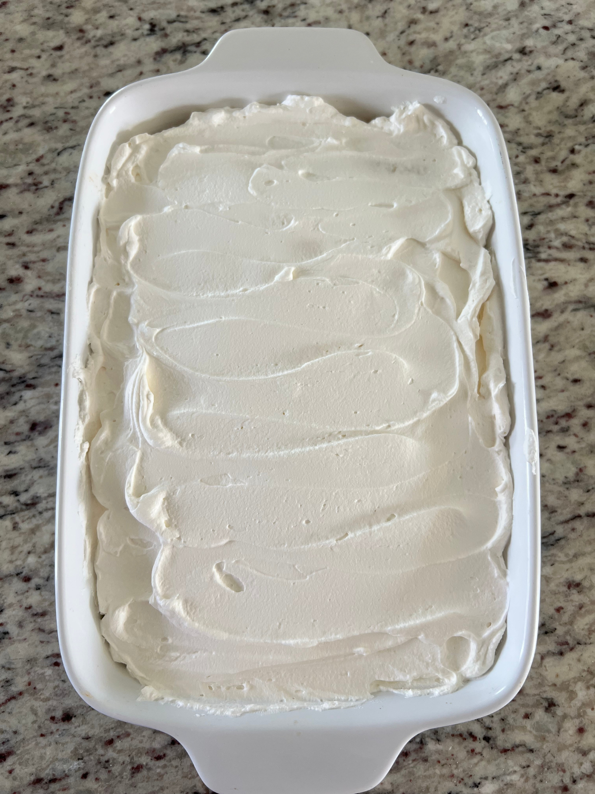 The sourdough tres leches cake is shown with whipped cream frosted over it.
