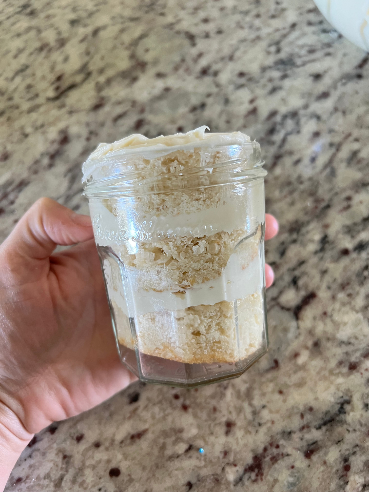 The sourdough cake has been layered in the jar with cake, frosting, cake, frosting. 
