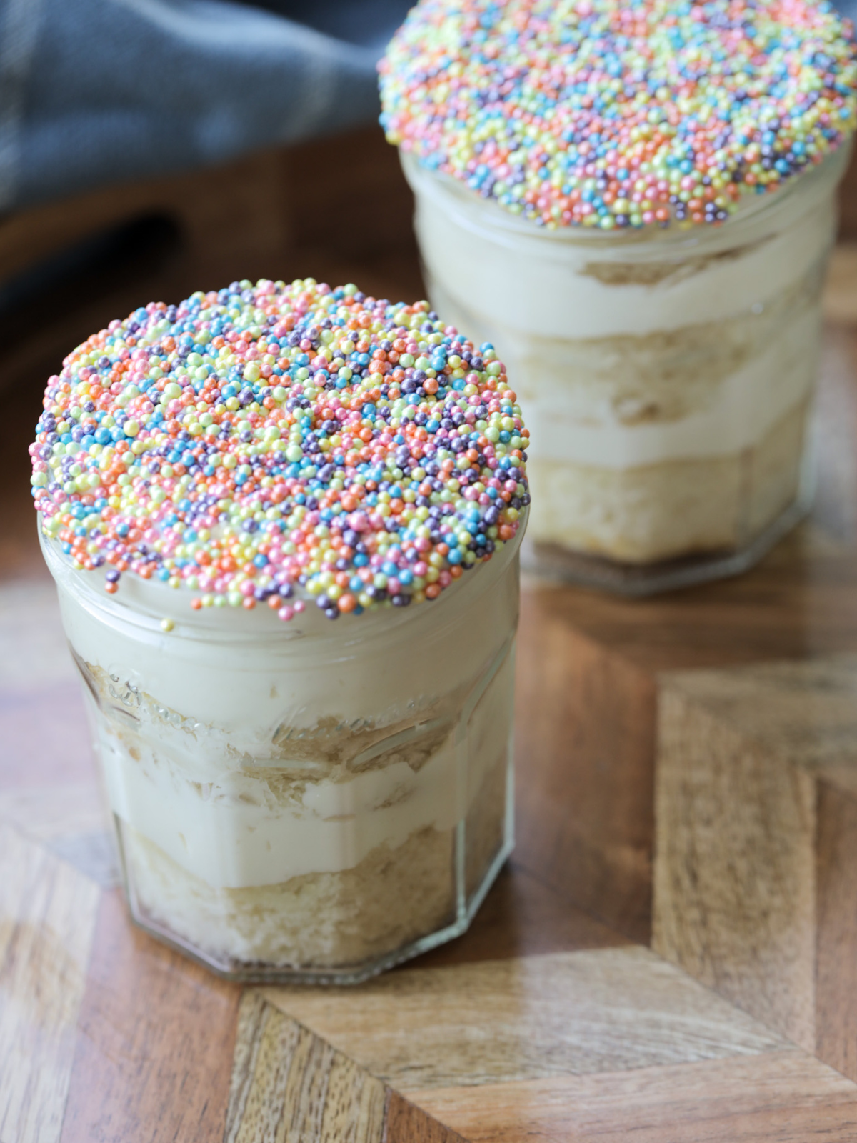 Two sourdough discard vanilla dot cakes sit in glass jelly jars. 