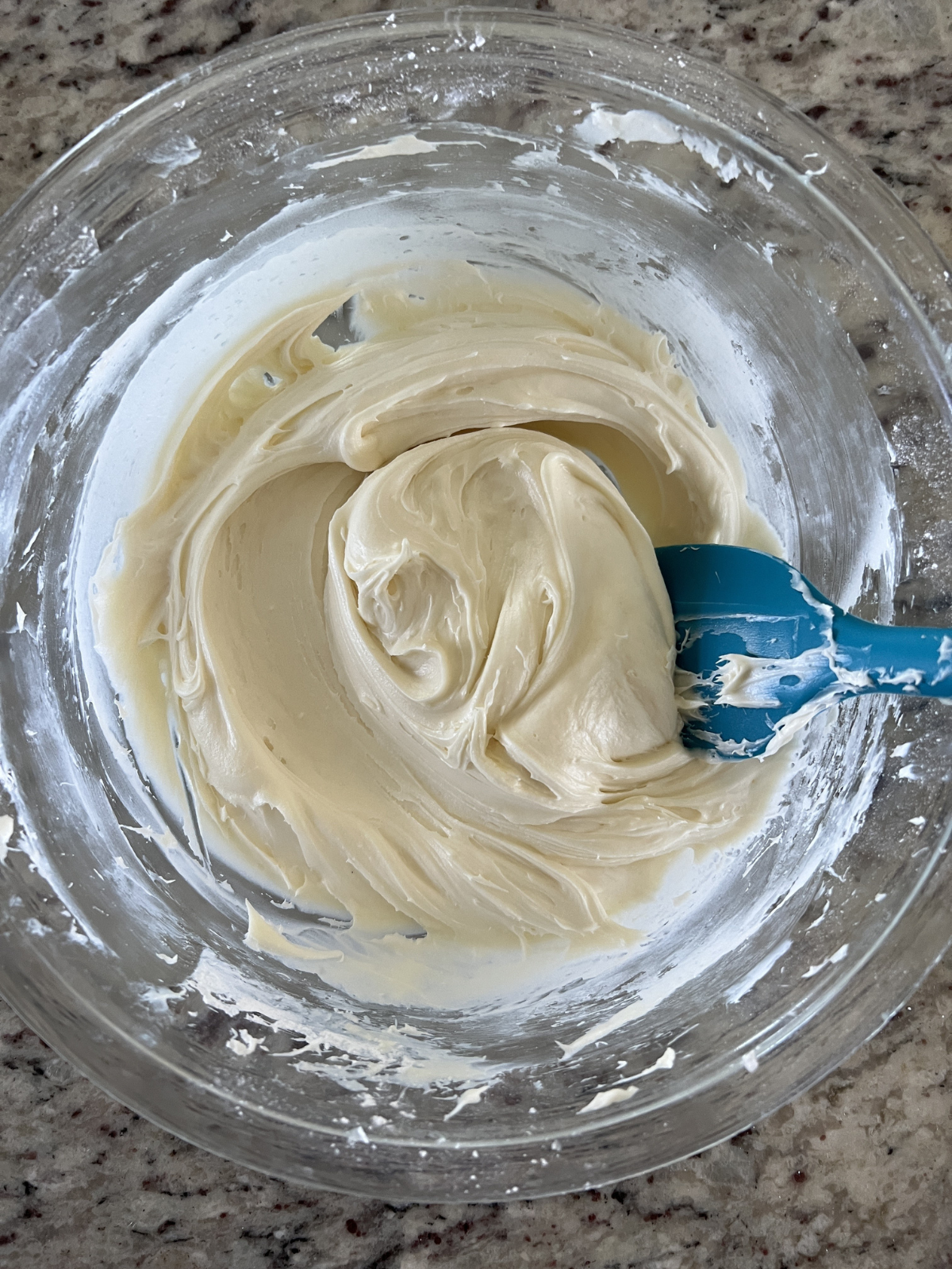 The vanilla cream cheese frosting sits in a glass mixing bowl.