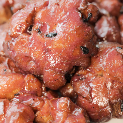 Several sourdough lemon blueberry fritters rest on a serving platter.