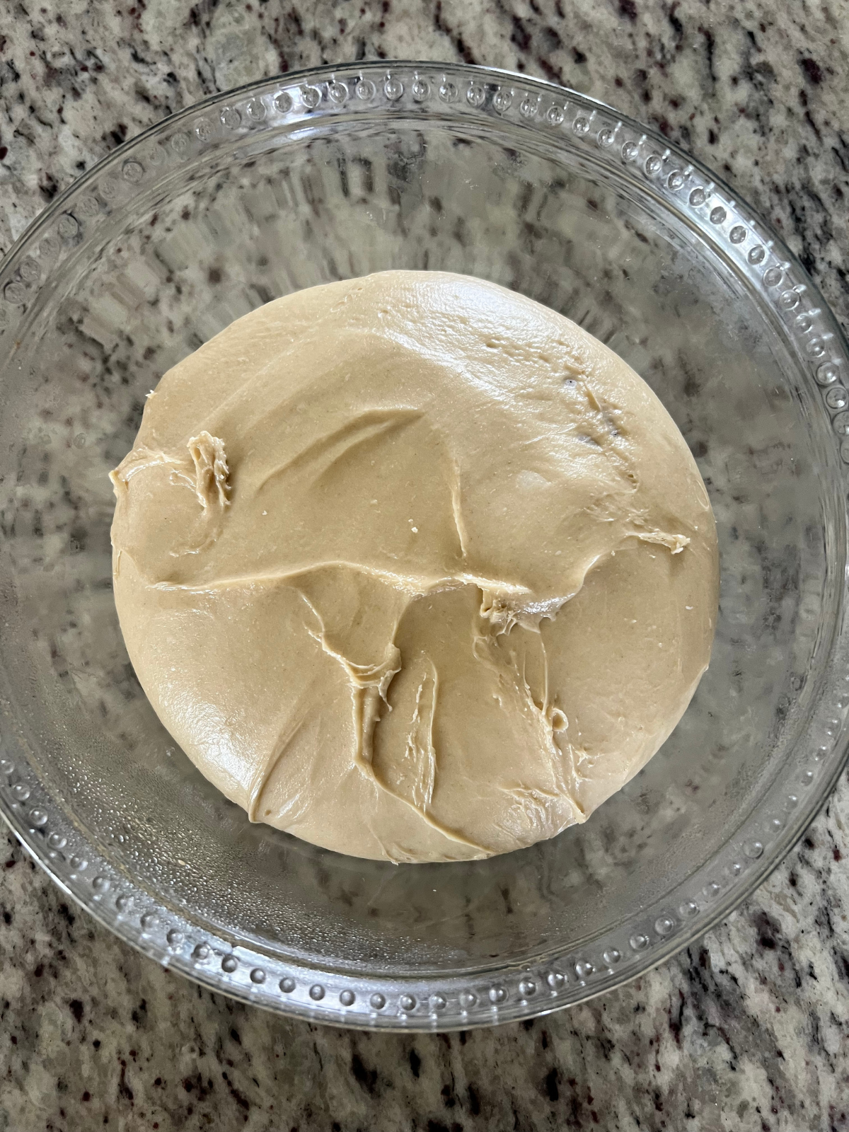 Sourdough lemon blueberry fritter dough rests fully fermented in a glass bowl.
