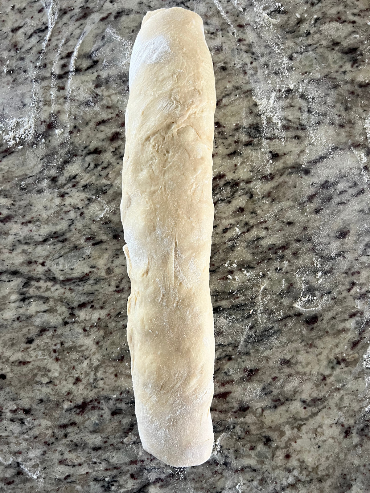 The sourdough blueberry lemon fritter dough has been rolled into a cylinder.