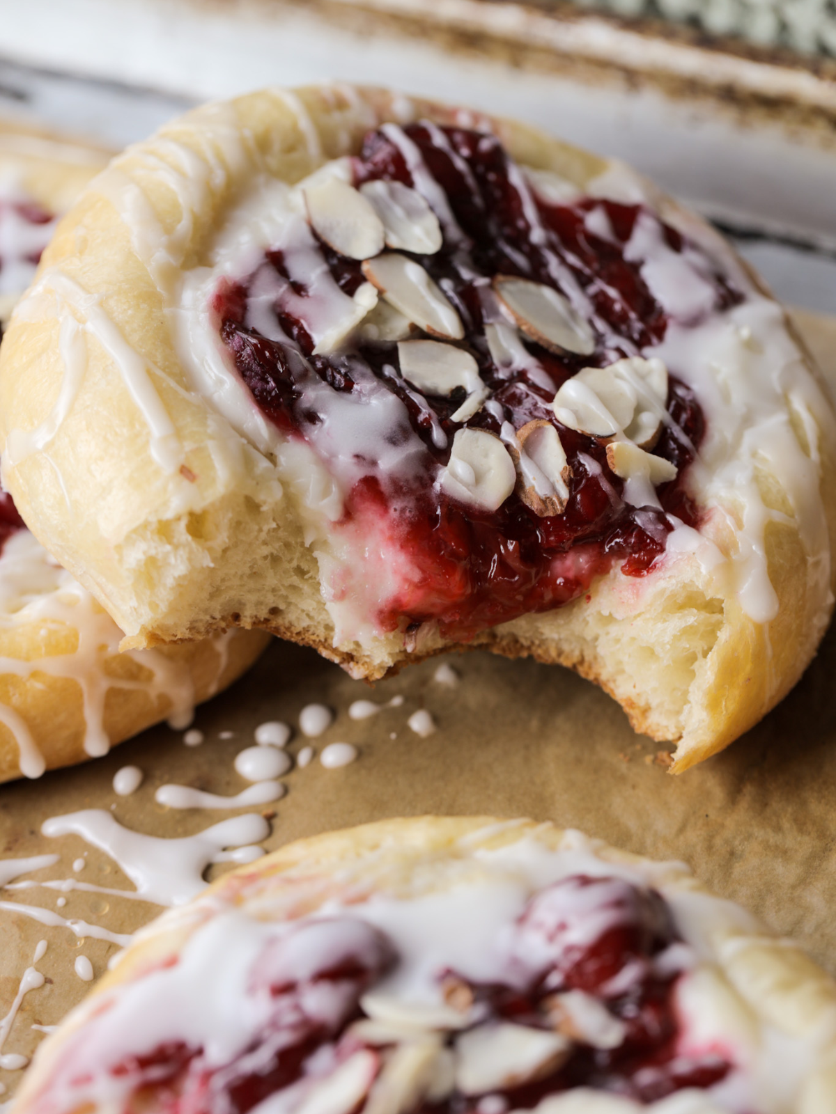 A close up of the crumb of these sourdough brioche cherry almond cream cheese buns that have had two bites taken out of them.