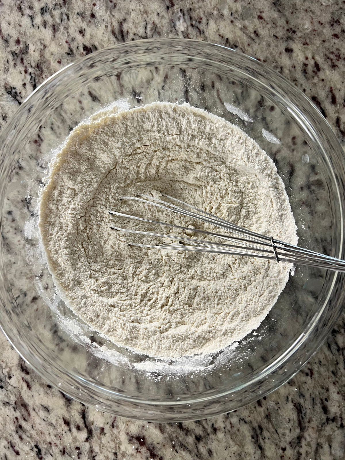 The dry ingredients for the sourdough discard blueberry crumble loaf sit in a glass mixing bowl.