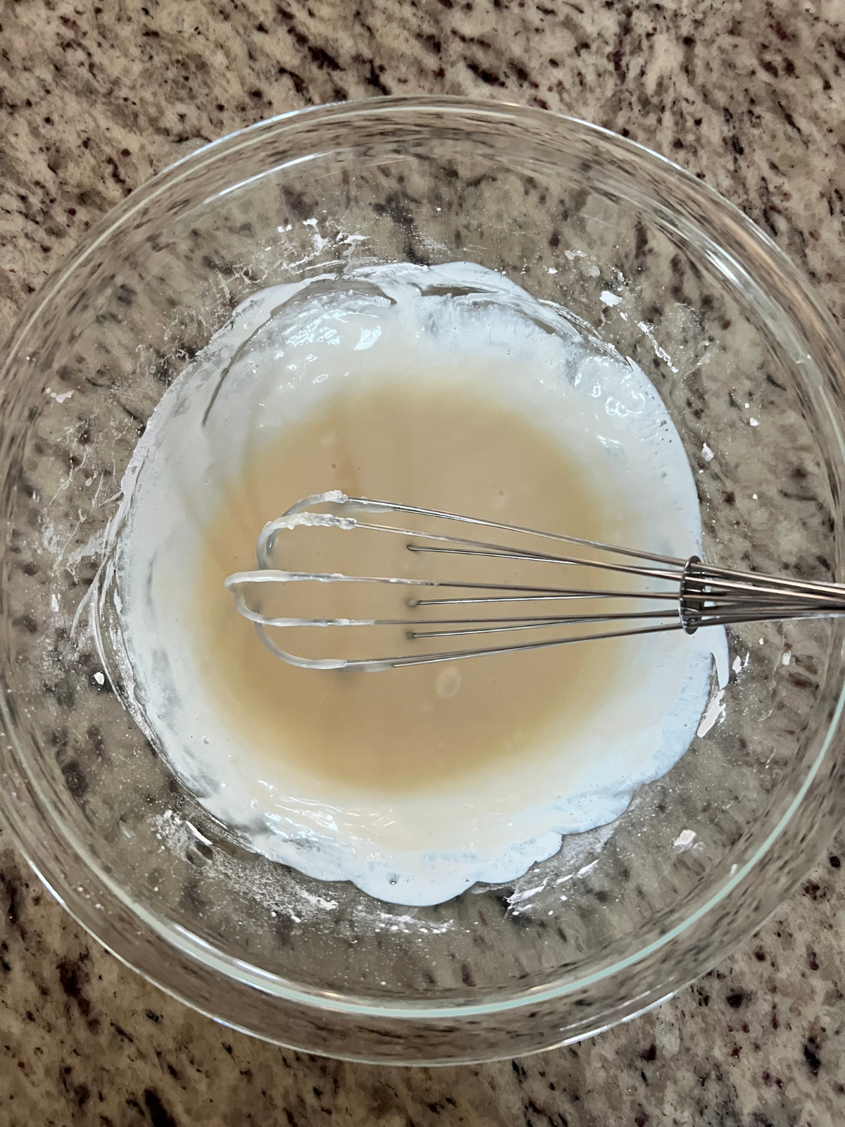 The vanilla icing sits in a glass mixing bowl.