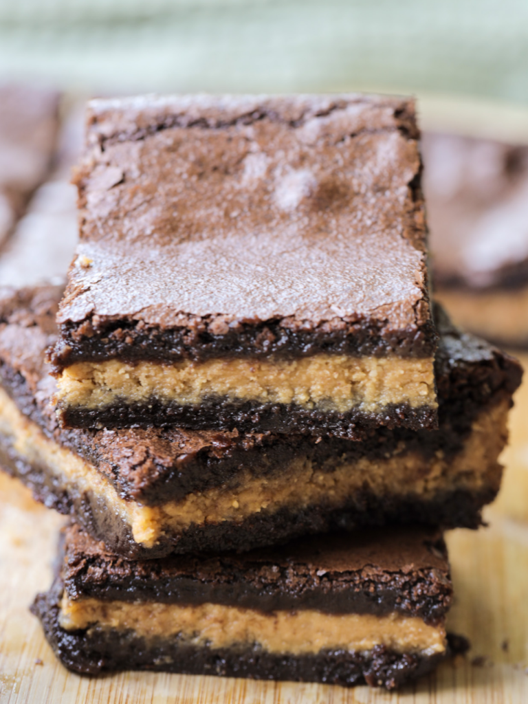 Three rich and chewy sourdough discard brownies with peanut butter centers are stacked on top of each other.