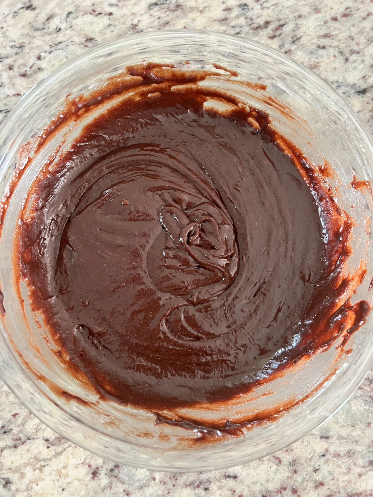 The sourdough discard brownie batter sits in a glass mixing bowl.