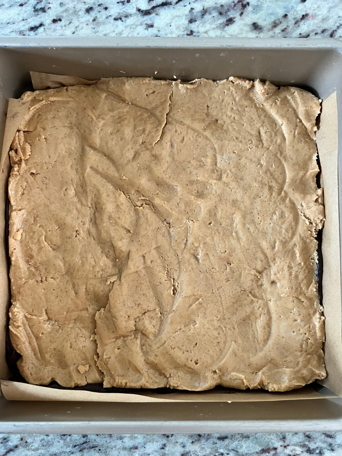 The peanut butter layer is shown on top of the bottom layer of the brownie batter.