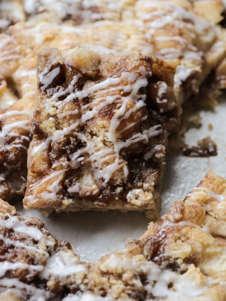 A slice of sourdough peach crumble focaccia shown with vanilla icing.