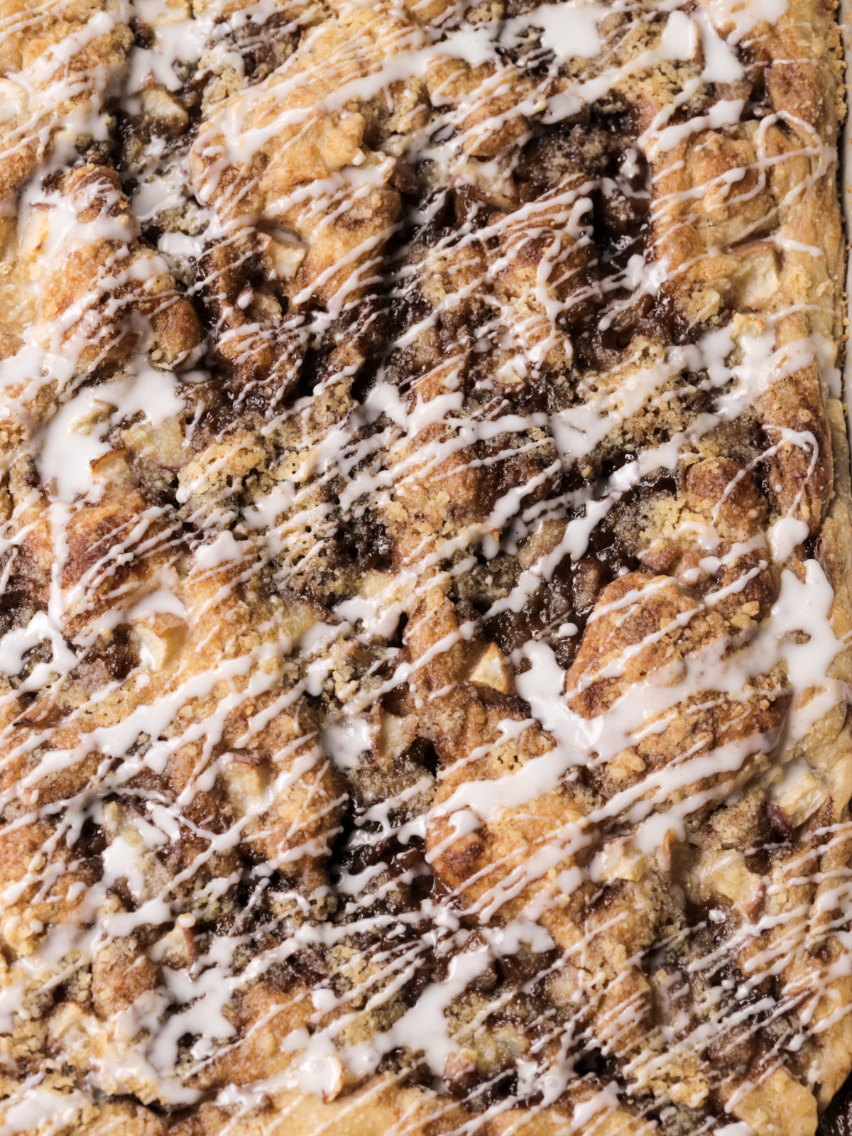 A closeup of the freshly baked sourdough peach crumble focaccia with vanilla icing is shown.