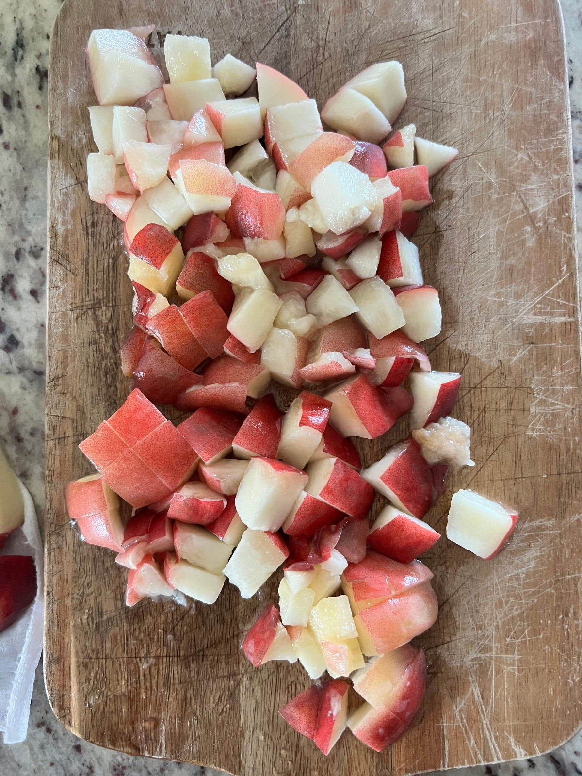 The freshly diced peaches are shown on a wooden cutting board.