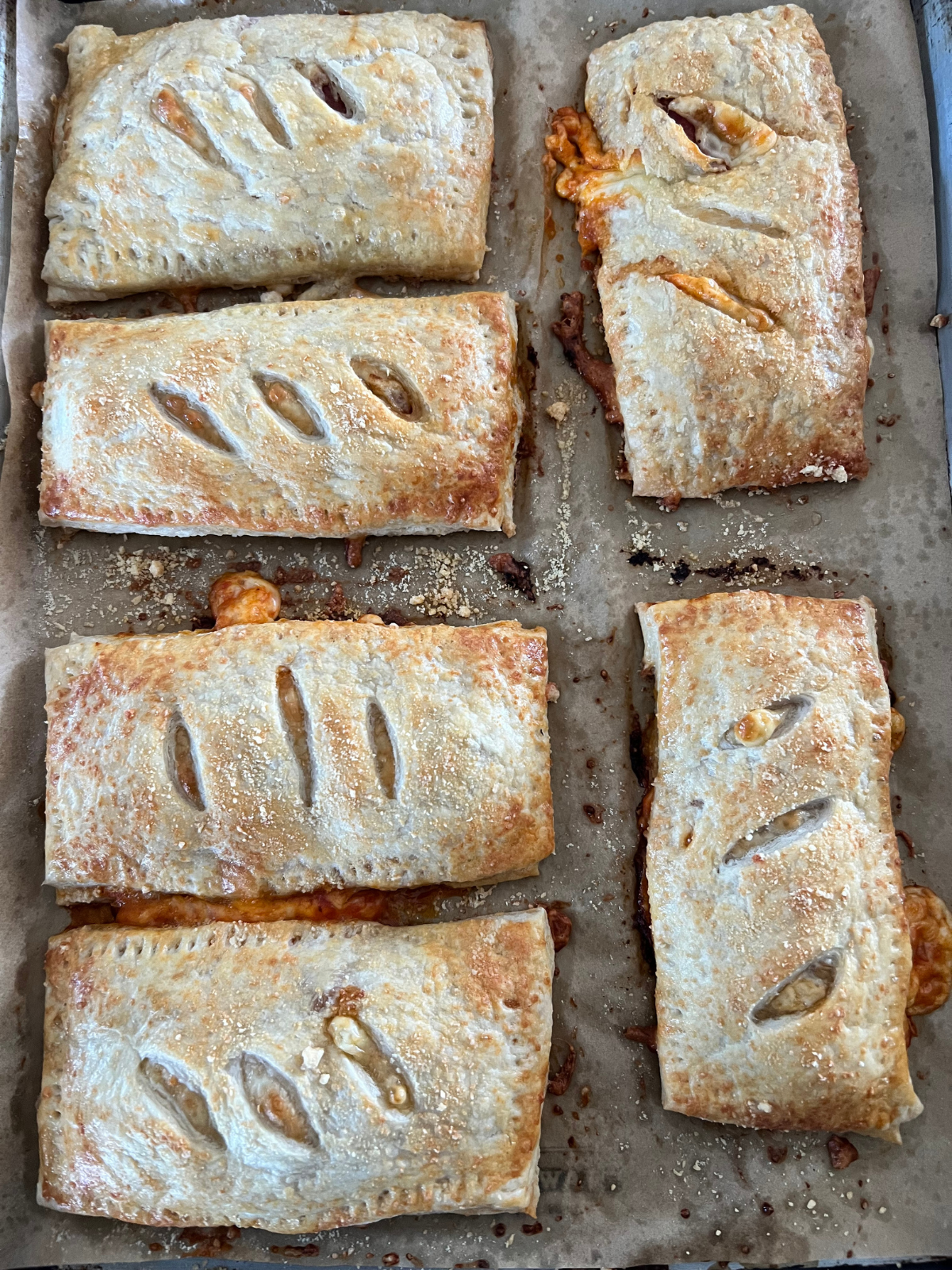 The sourdough pepperoni pizza hot pockets are fresh out of the oven on top of a parchment paper lined baking sheet.