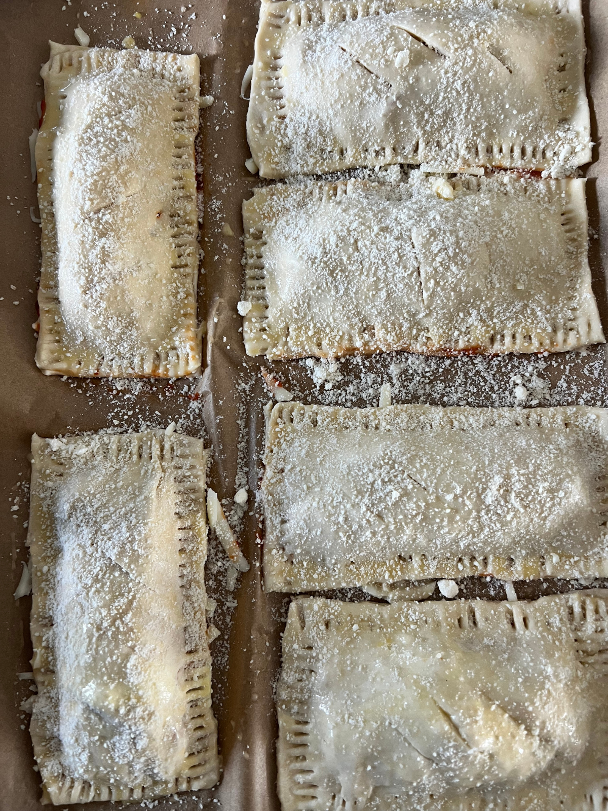 The sourdough discard pizza hot pockets are shown after freezing. Half have slits cut into them and the parmesan cheese was added prior to freezing.