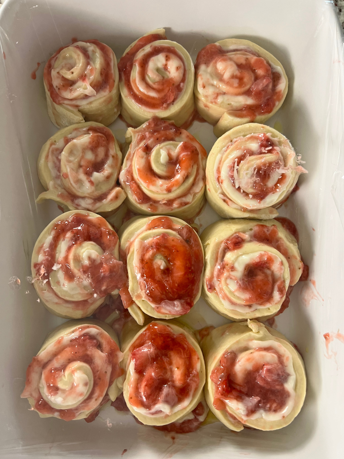 The sourdough strawberry cheesecake sweet rolls are shown shaped sitting in the baking pan before their second rise.