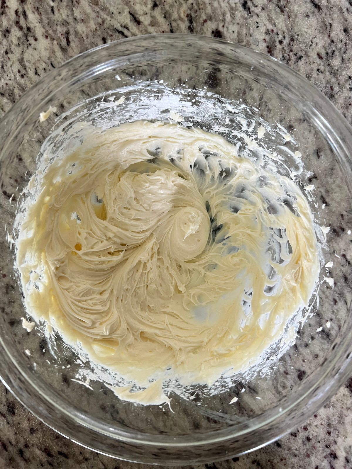 The sweet cream cheese filling sits mixed in a glass bowl.