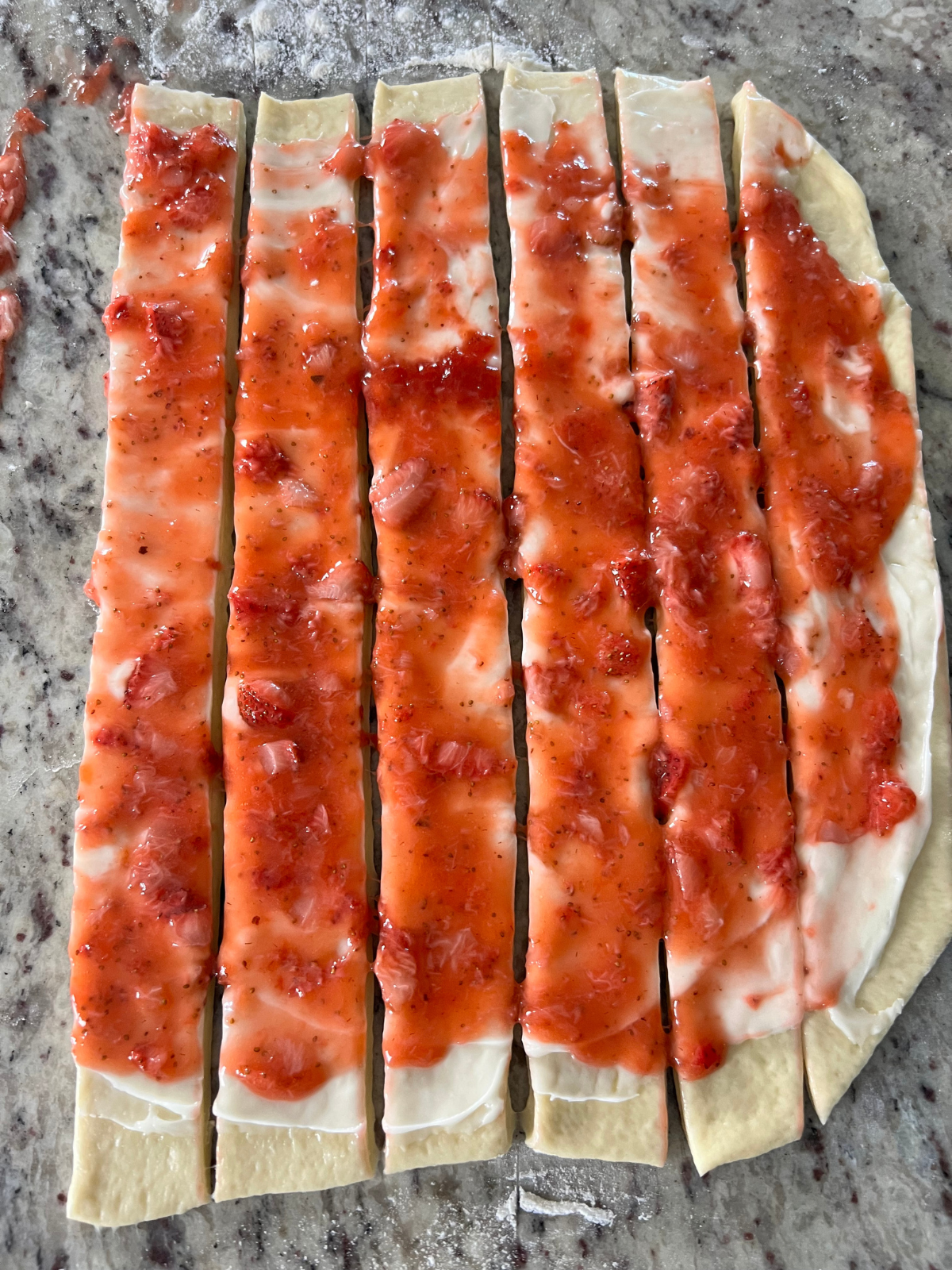 The dough has been cut into strips, which you will roll and then turn into sweet rolls.
