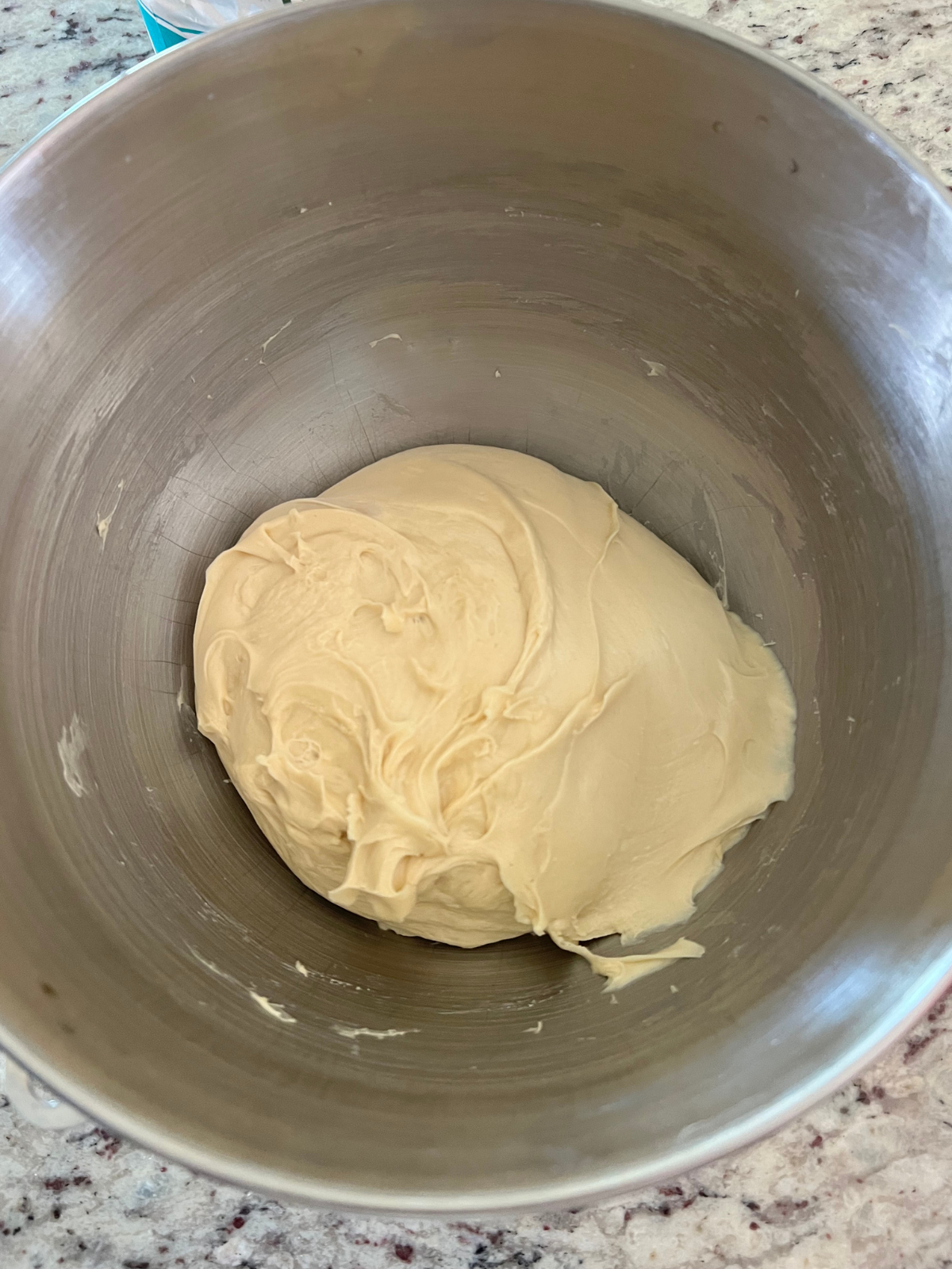 Sourdough brioche sweet roll dough sits in the bowl of a stand mixer after being kneaded.