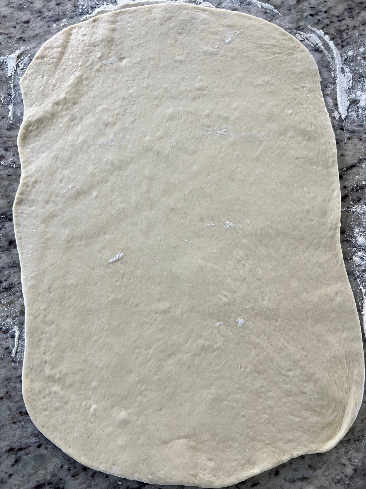 The sourdough strawberry cheesecake sweet roll dough has been rolled into a rectangle.
