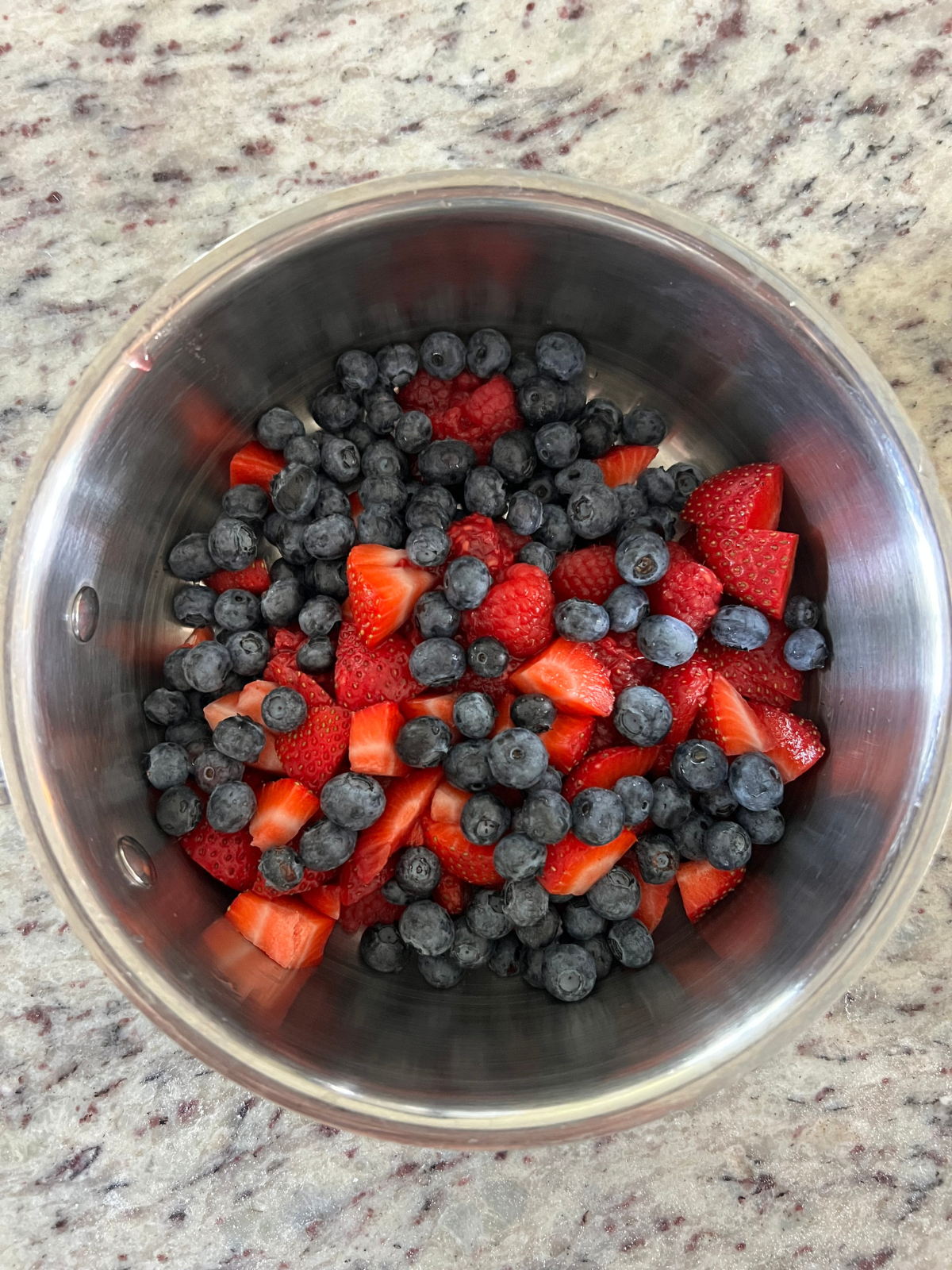 The mixed berries are shown in the saucepan. They will be topped with cornstarch and sugar and bake over the stove.