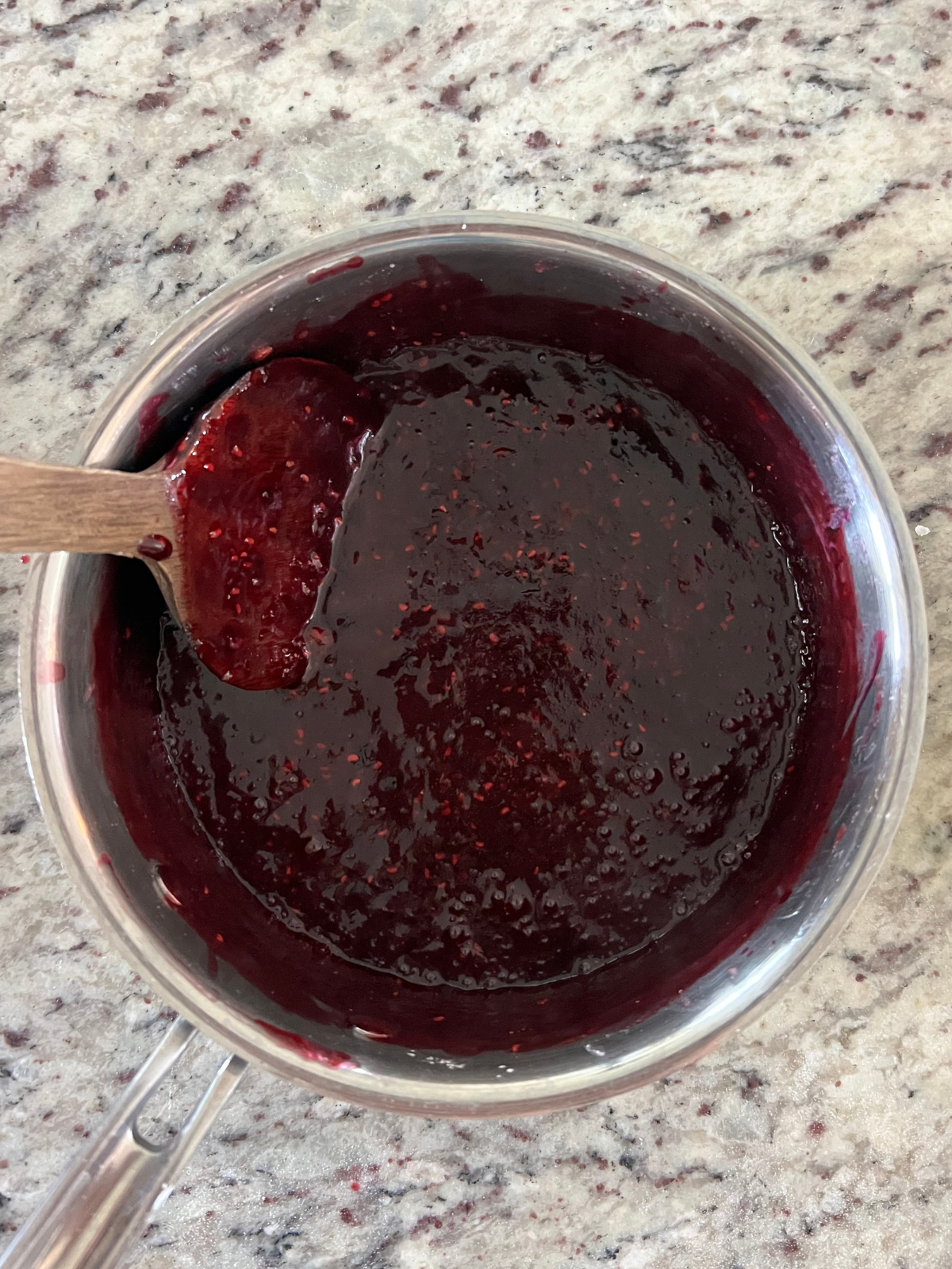 The raspberry, blueberry, and strawberry sauce is shown in the saucepan after getting cooked over the stove.
