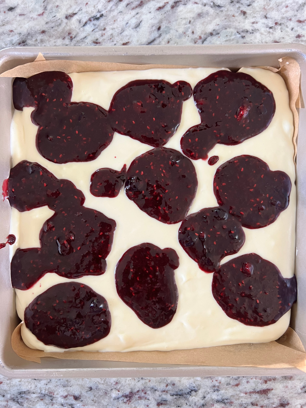 Dollops of the berry sauce is shown over the cheesecake filling.
