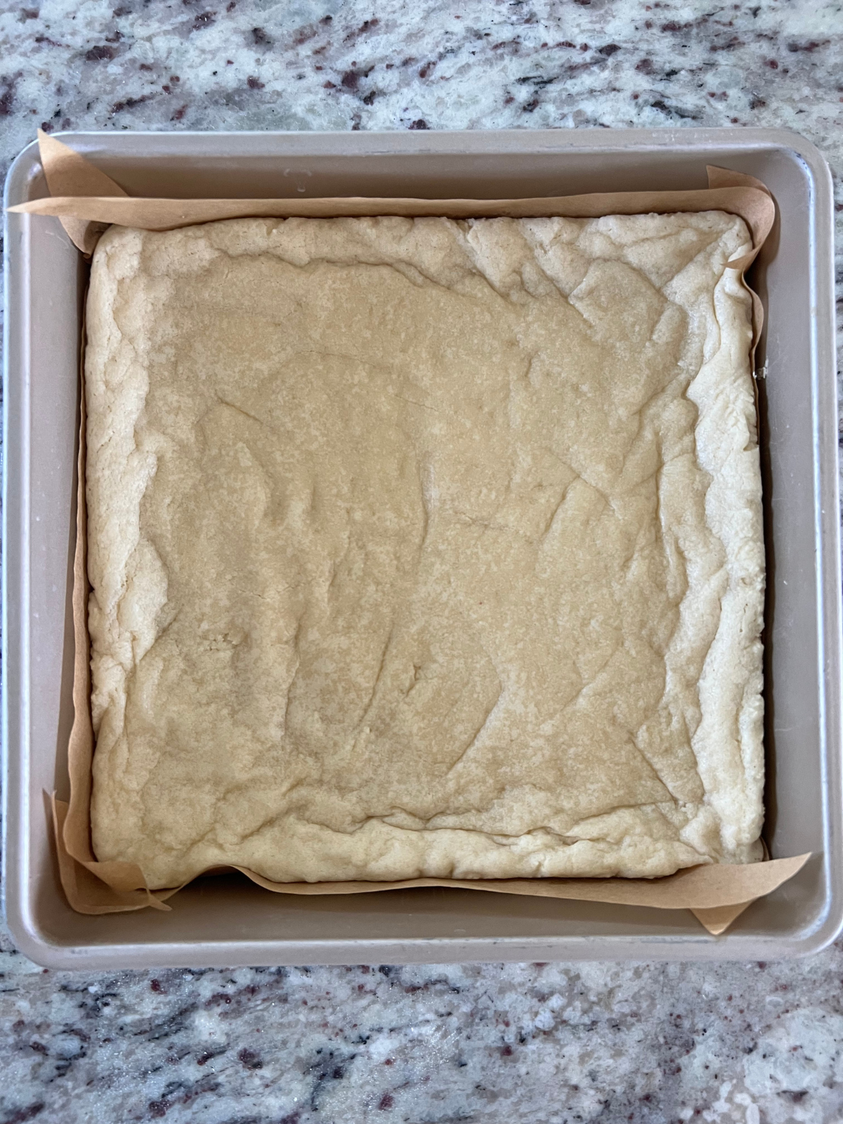 The par baked sourdough sugar cookie crust is shown in the 9x9 baking pan.