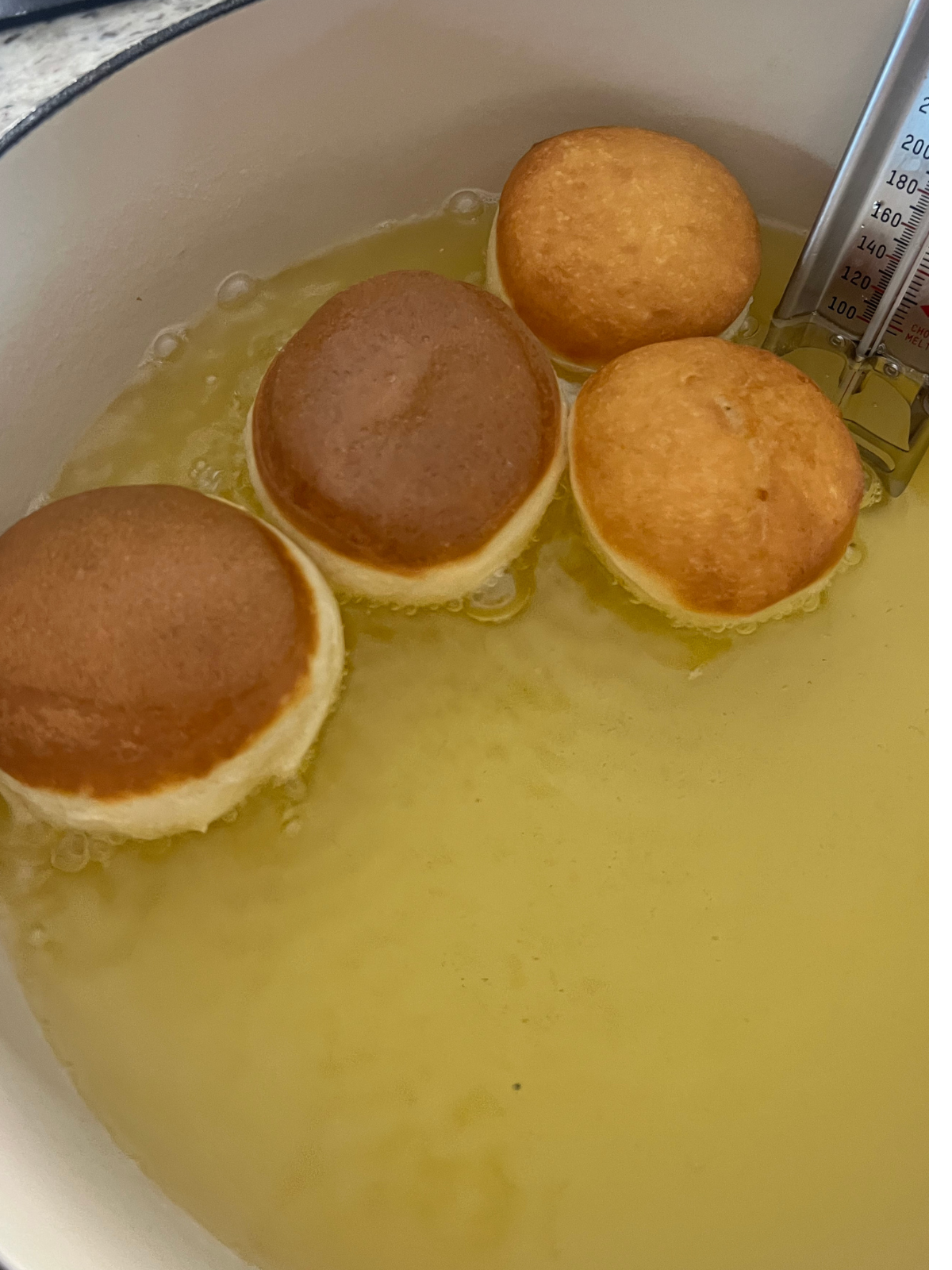 The sourdough donuts are shown in the oil frying.