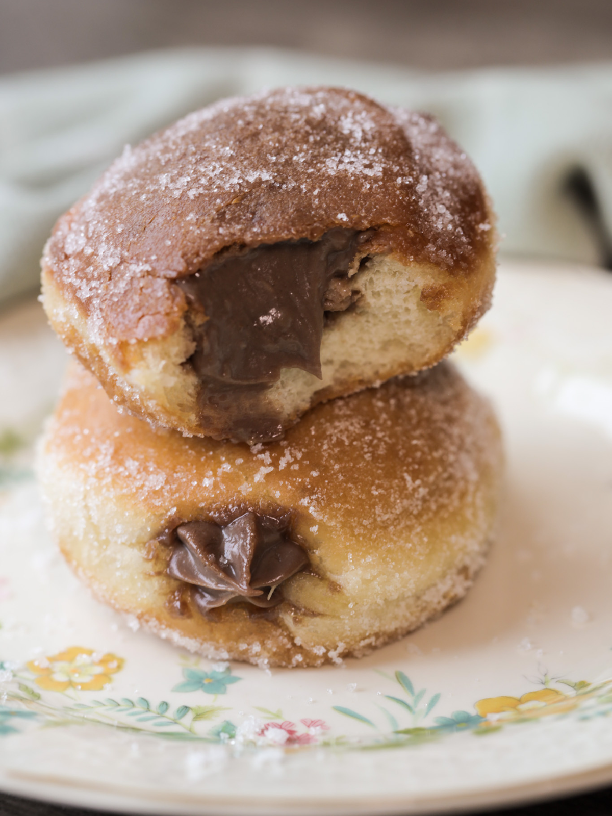 Two sourdough brioche donuts with a homemade chocolate custard filling are stacked on a plate. 