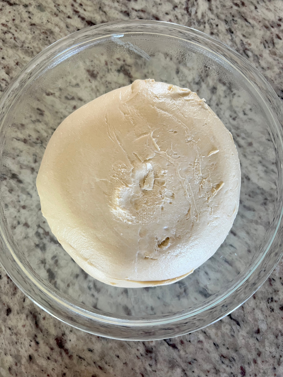 The bulk fermented sourdough dough is shown in a glass mixing bowl. It has been refrigerated overnight.