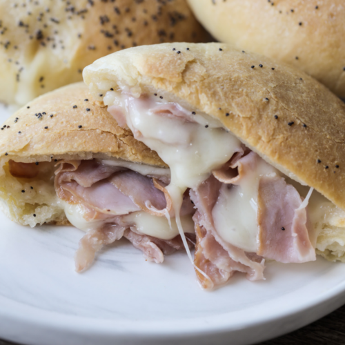 Sourdough ham and Swiss cheese pocket is shown cut in half with melty Swiss cheese and sliced ham.