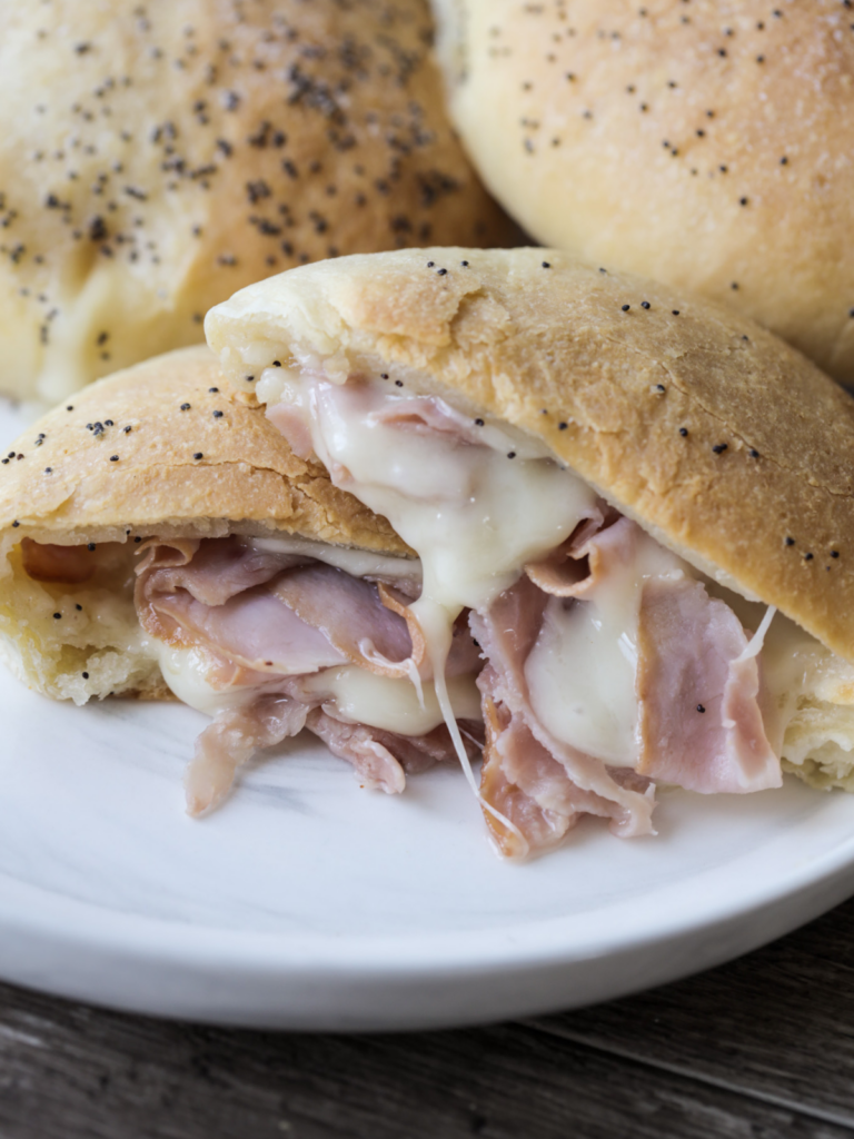 Sourdough ham and Swiss cheese pocket is shown cut in half with melty Swiss cheese and sliced ham.