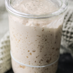 A jar of very active and bubbly sourdough starter sits in a glass Weck jar.