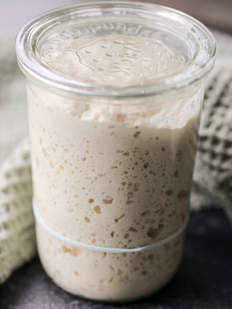 A jar of very active and bubbly sourdough starter sits in a glass Weck jar.
