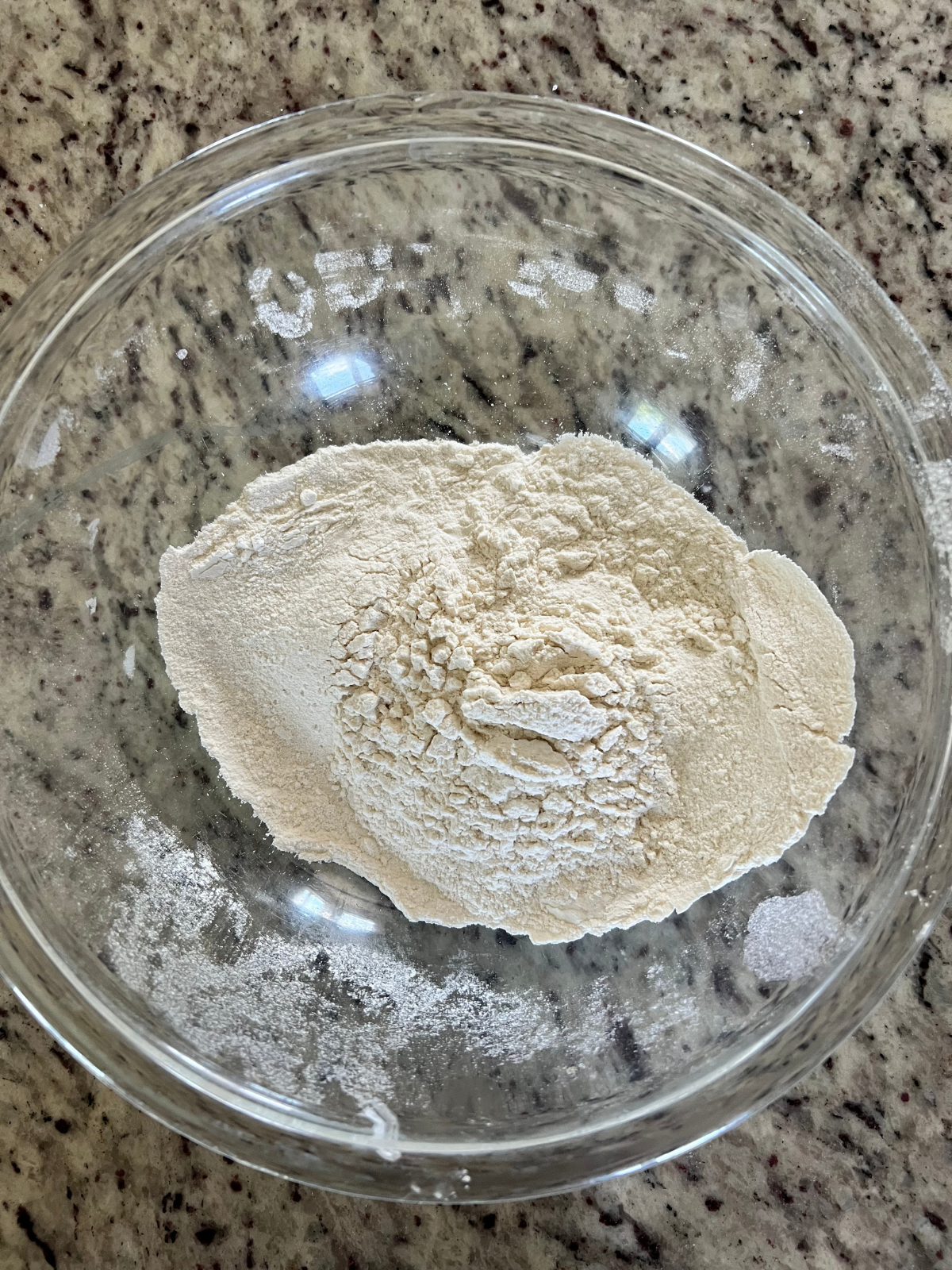 The dry ingredients for the sourdough discard blueberry muffins sit in a glass mixing bowl.
