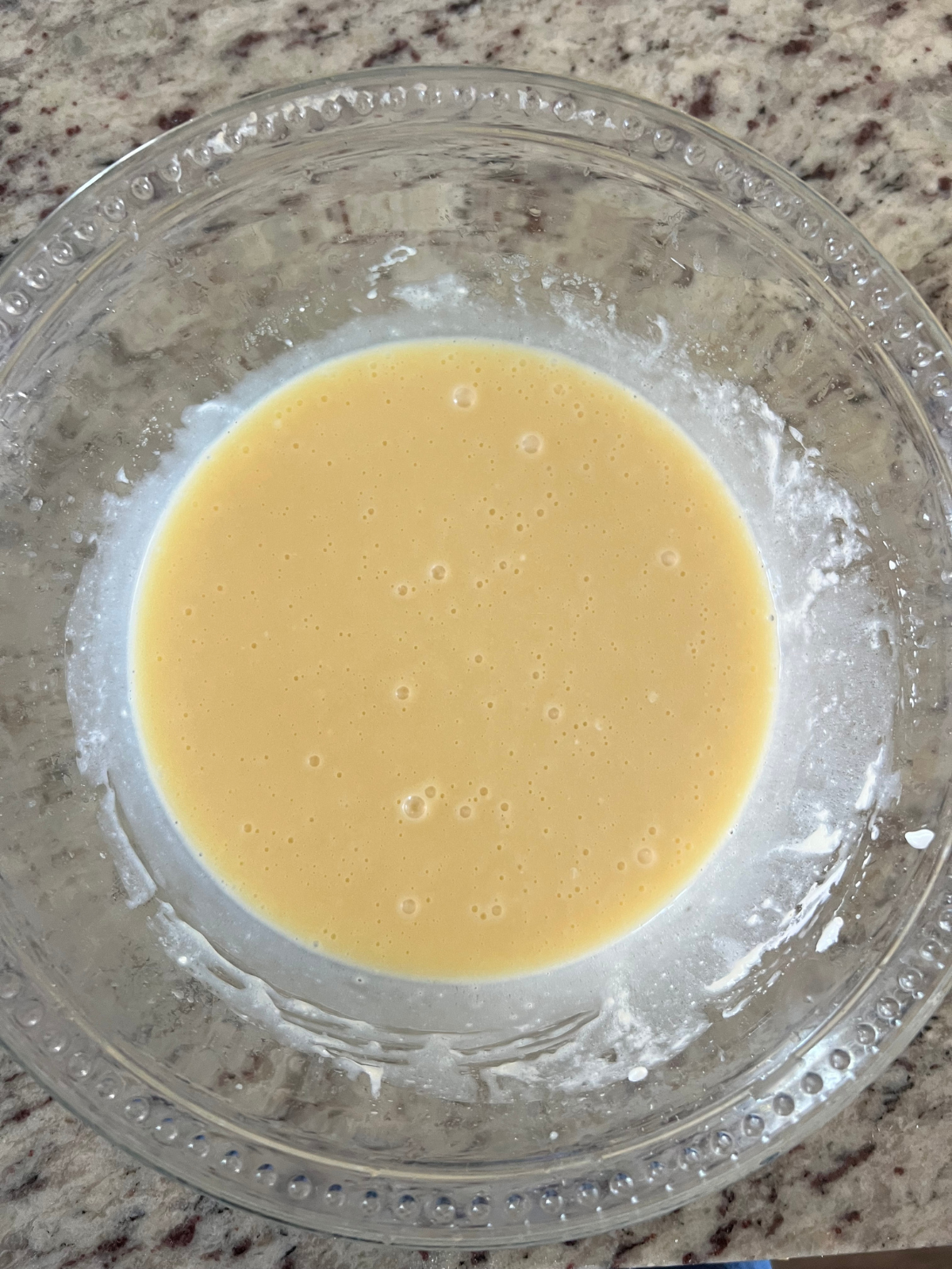 The wet ingredients for the sourdough discard blueberry muffins sit in a glass mixing bowl.