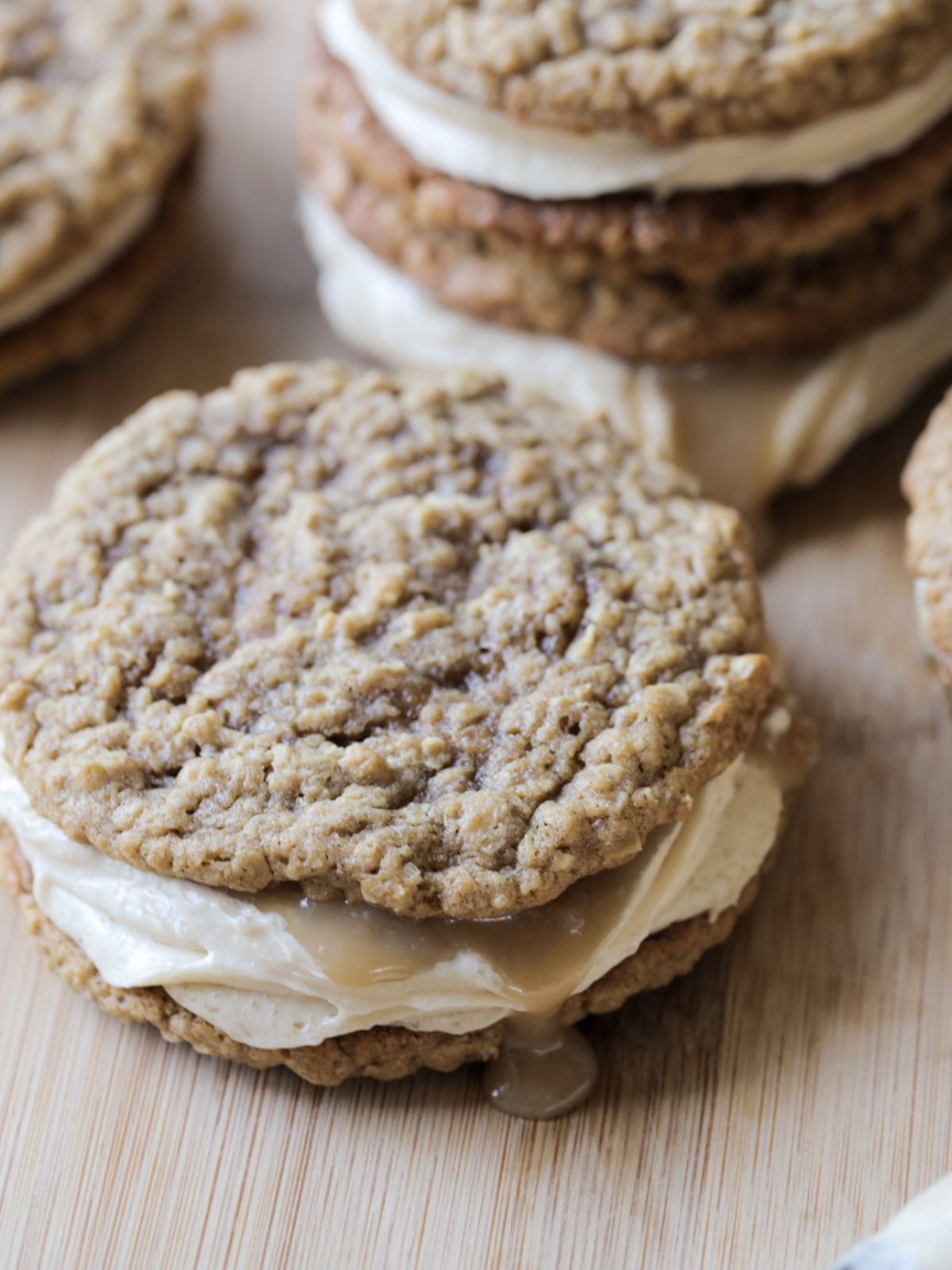 A closeup of one sourdough brown butter caramel apple oatmeal cream pie is shown with caramel drizzled over the side. 